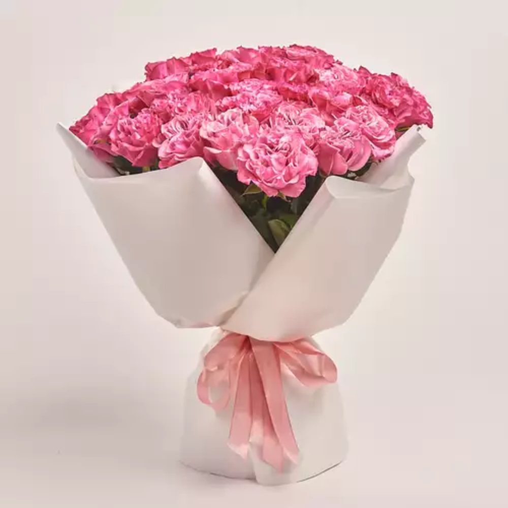 Full bouquet of fresh pink carnations wrapped in white paper with a soft pink ribbon