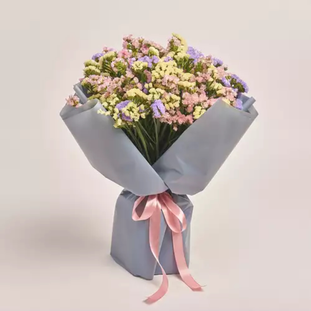 Elegant bouquet of fresh roses wrapped in white paper with a soft pink satin ribbon