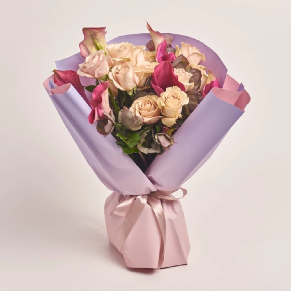 Elegant bouquet of cream roses and pink calla lilies wrapped in lavender paper and tied with a soft pink ribbon