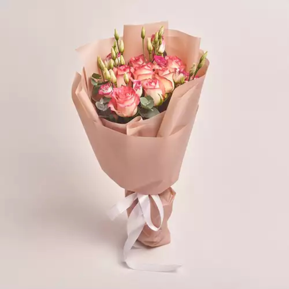 Elegant peach and pink rose bouquet with buds wrapped in soft beige paper and tied with a white ribbon