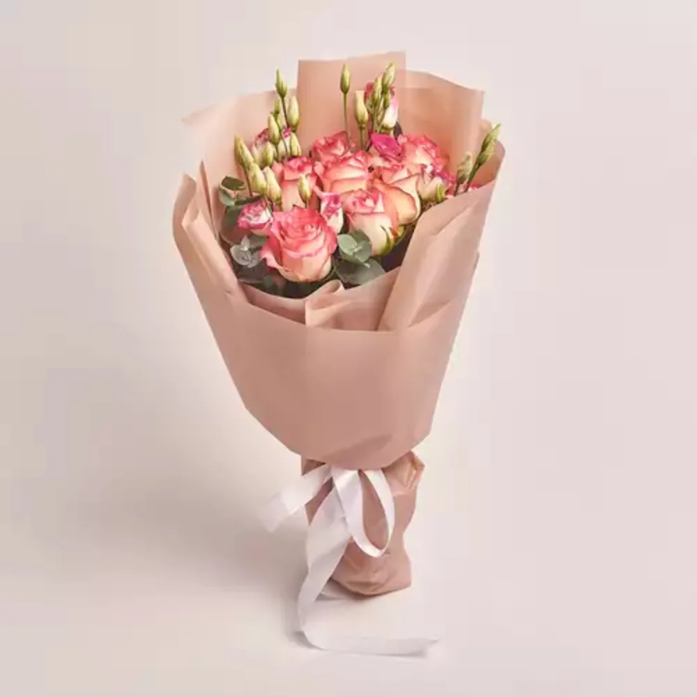 Elegant peach and pink rose bouquet with buds wrapped in soft beige paper and tied with a white ribbon