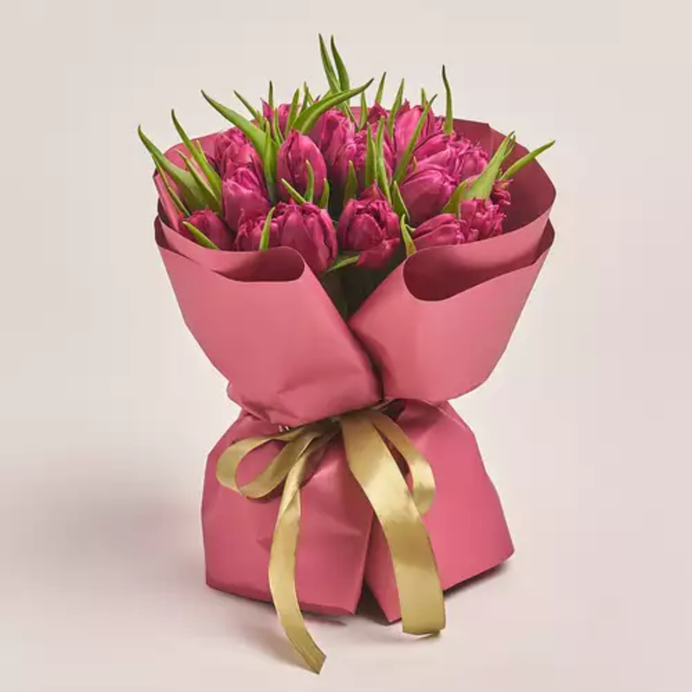 Bouquet of vibrant pink tulips with green leaves wrapped in deep pink paper