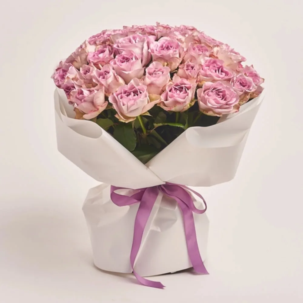 Elegant bouquet of pink roses wrapped in white paper and tied with a purple ribbon