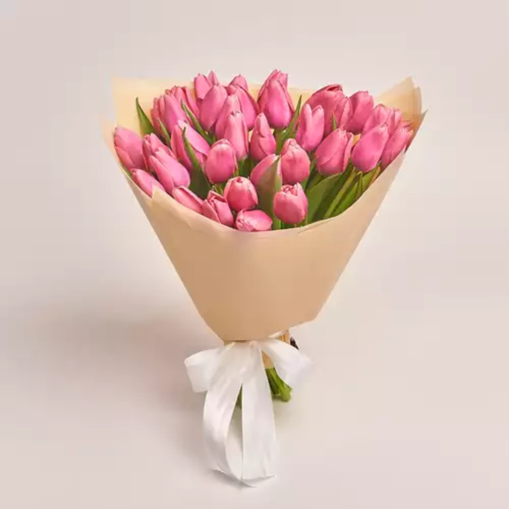 Beautiful bouquet of fresh pink tulips wrapped in beige paper with a white ribbon, elegant floral gift by Favish Blooms Dubai