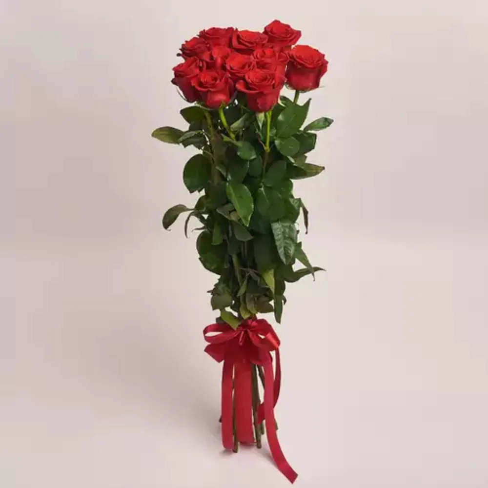 Hand-tied bouquet of fresh red roses with green foliage and a red ribbon, elegant romantic flower gift by Favish Blooms Dubai