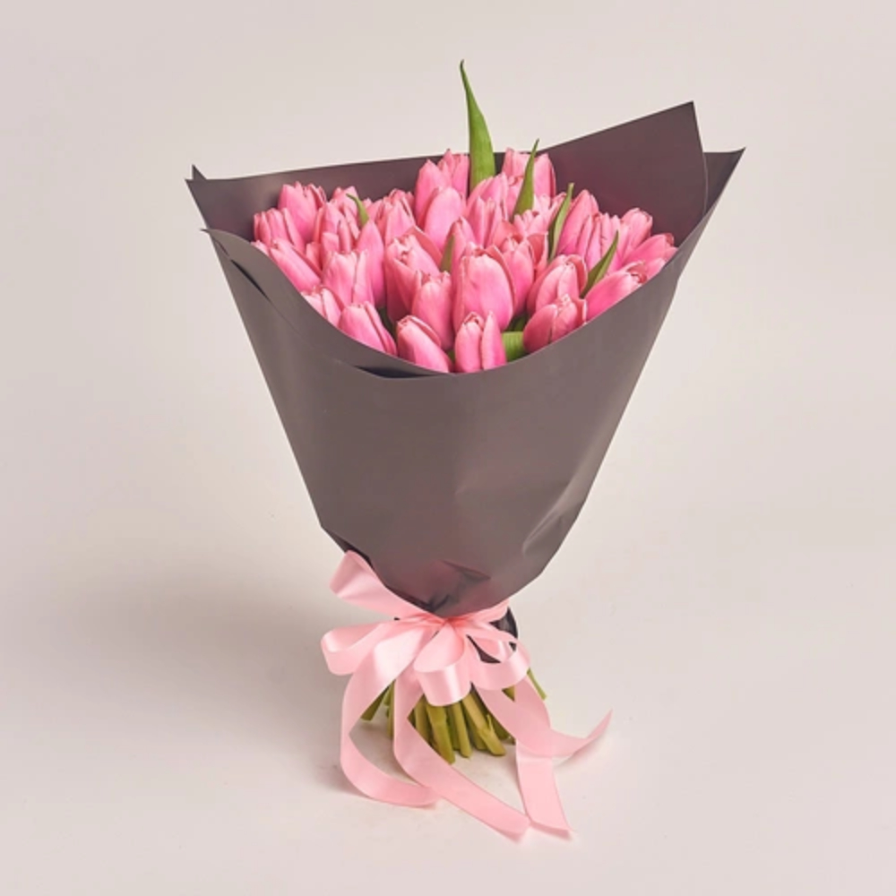 A bouquet of pink tulips wrapped in dark grey paper and tied with a pink ribbon