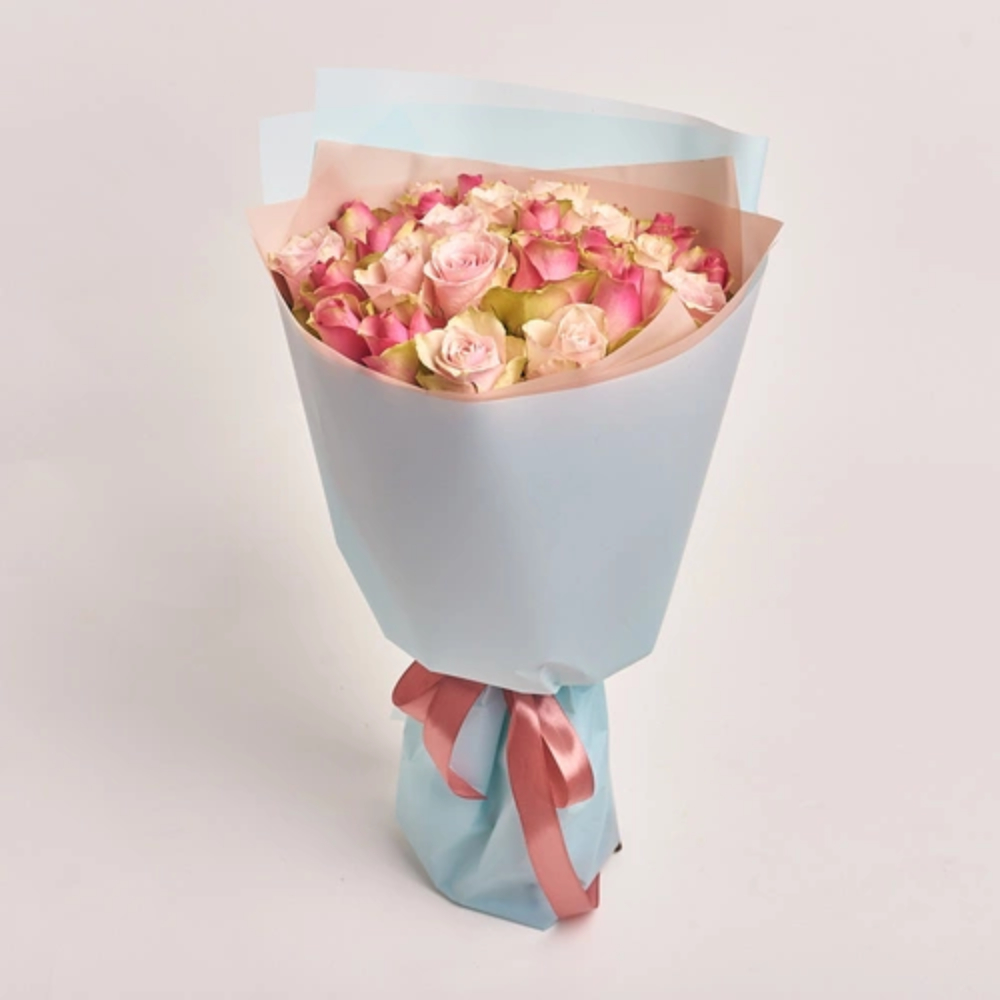 A bouquet of pink and cream roses wrapped in light blue and pink paper tied with a rose pink satin ribbon
