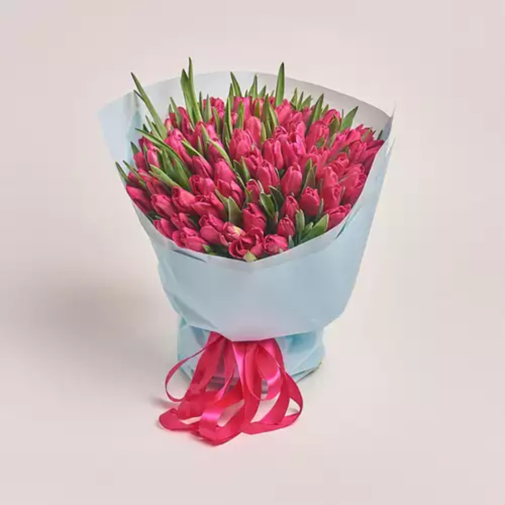 A large bouquet of pink tulips wrapped in light blue paper and tied with a pink ribbon