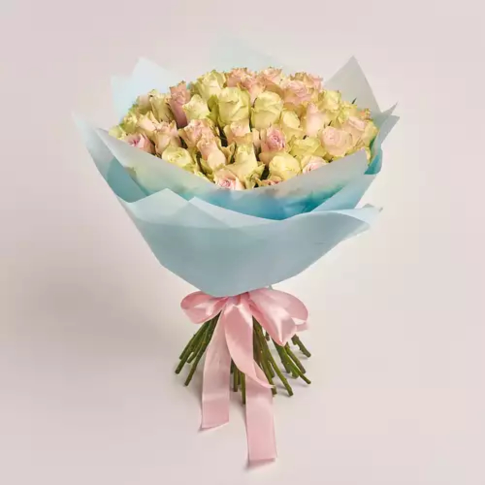 A bouquet of cream and pink roses wrapped in light blue paper and tied with a pink satin ribbon