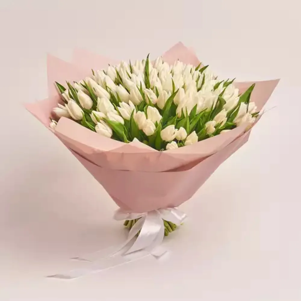 A large bouquet of white tulips wrapped in pink paper and tied with a white ribbon
