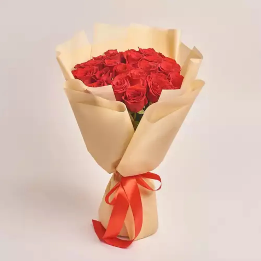 A bouquet of red roses wrapped in cream paper and tied with a red satin ribbon