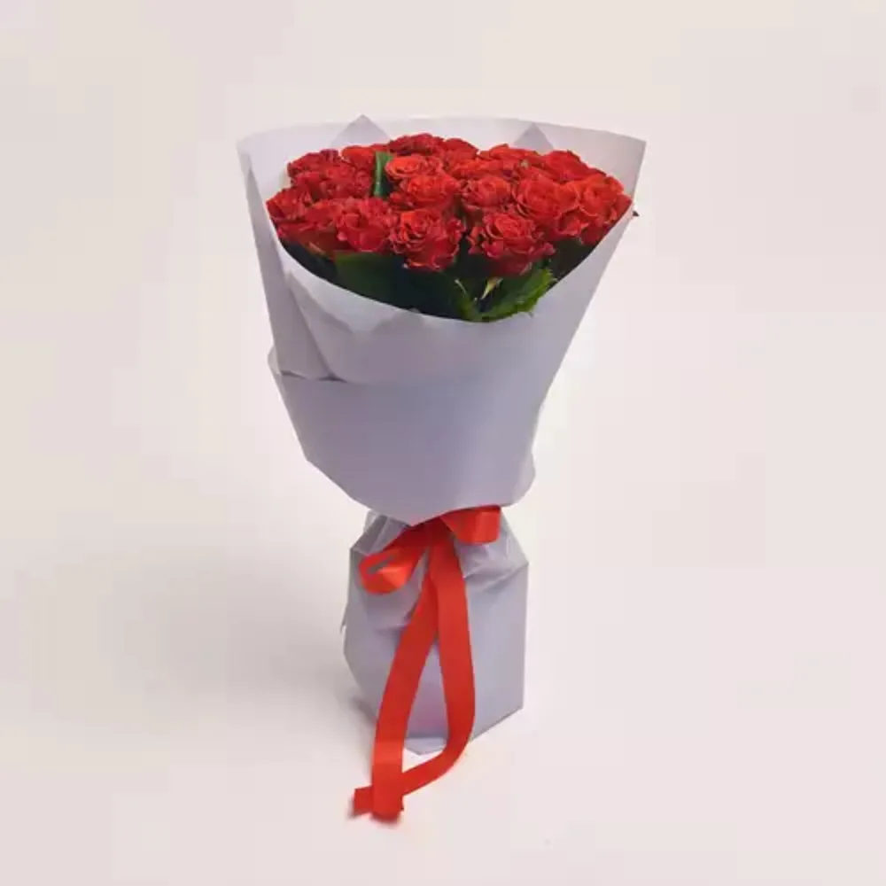 A bouquet of red roses wrapped in white paper and tied with a red satin ribbon