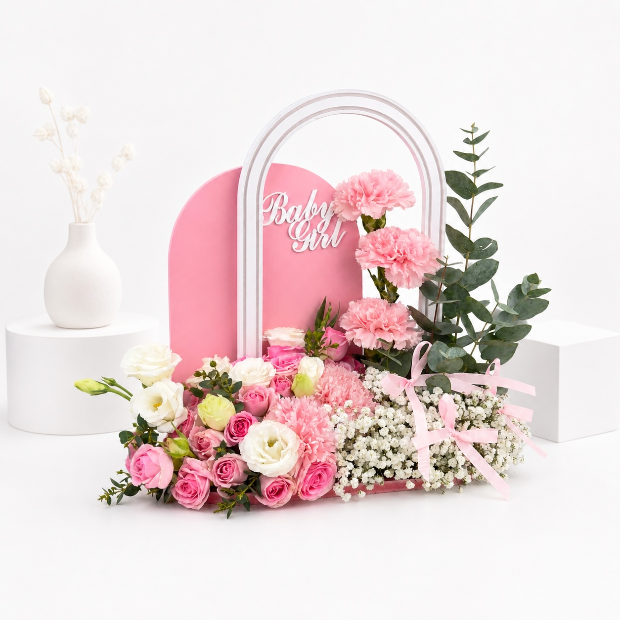 Luxury Welcome Baby Girl floral arrangement featuring pink carnations, pink roses, white lisianthus, baby’s breath, and eucalyptus in a modern pink acrylic tray with “Baby Girl” topper