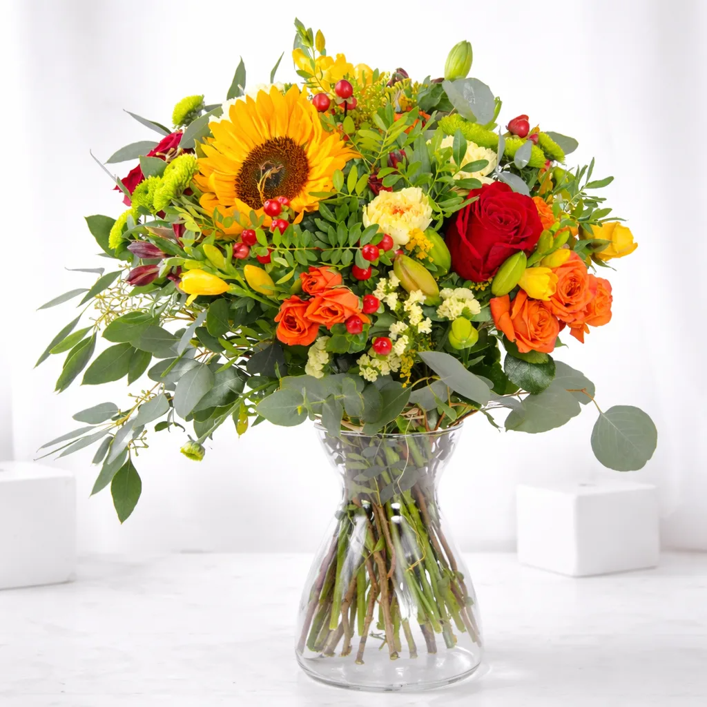 Bright congratulations flower arrangement with sunflowers, roses, and eucalyptus in a glass vase, perfect for celebrating special achievements.