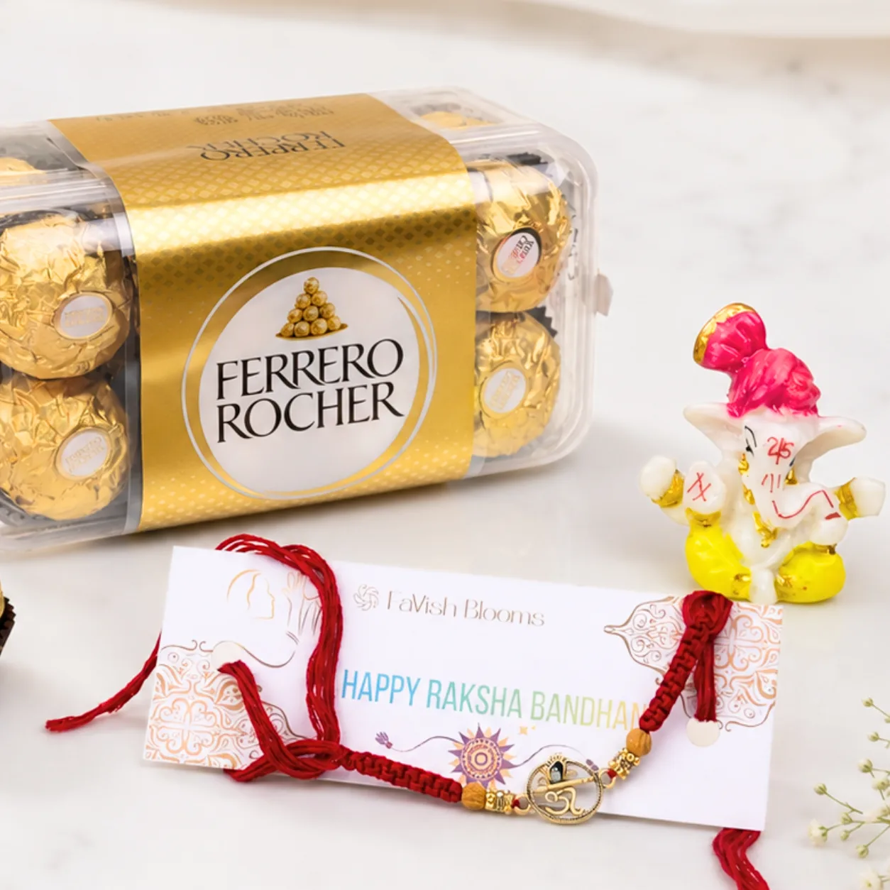Elegant Om design Rakhi displayed with a Ferrero Rocher chocolate box and festive Raksha Bandhan accessories.
