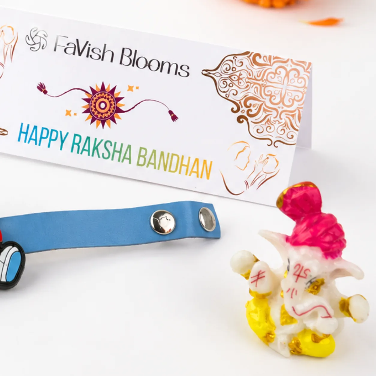 Close-up of blue Doraemon spinner Rakhi paired with a small Ganesha idol and traditional Rakhi essentials.