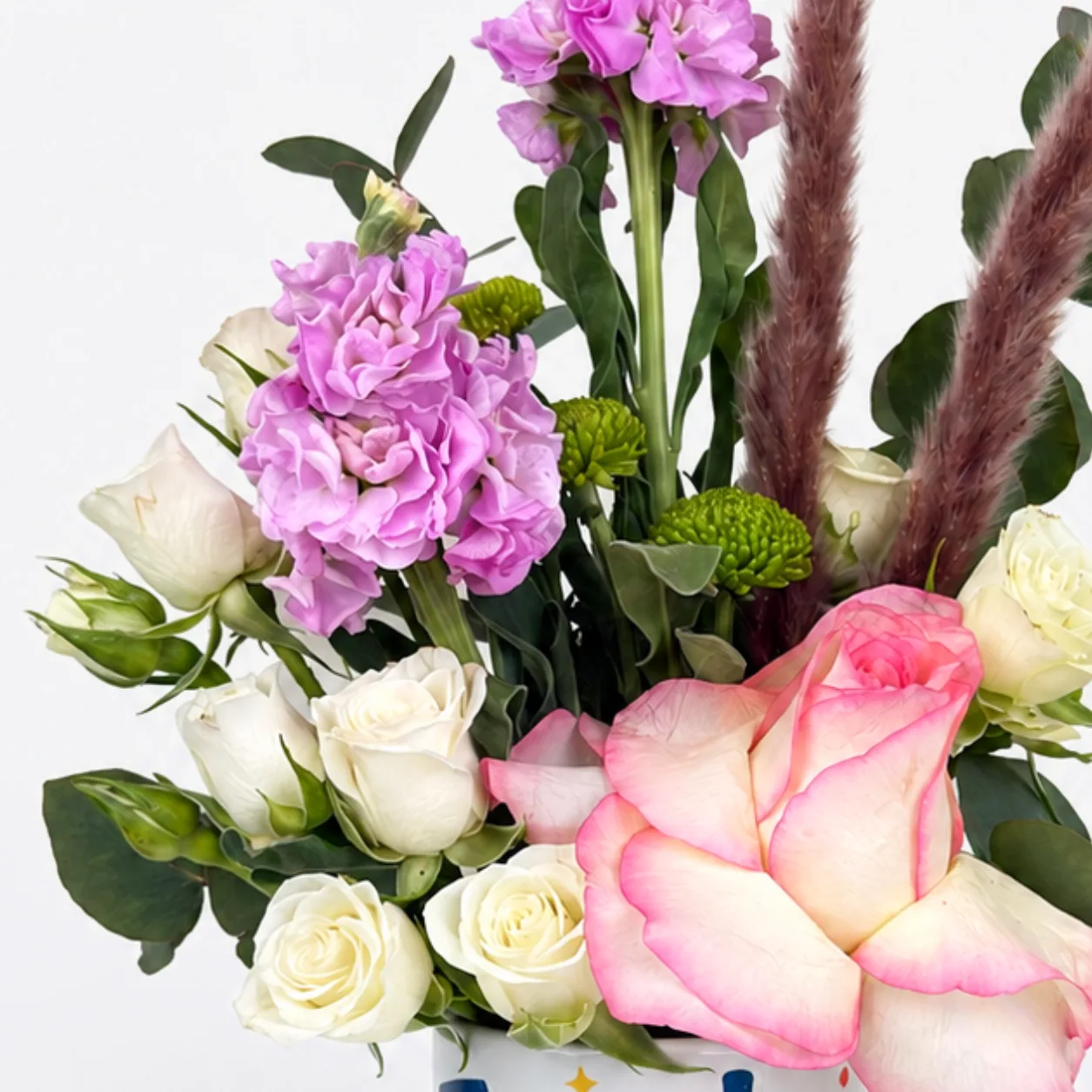 Colorful teacher flower arrangement with roses, seasonal blooms and decorative greenery in a mug