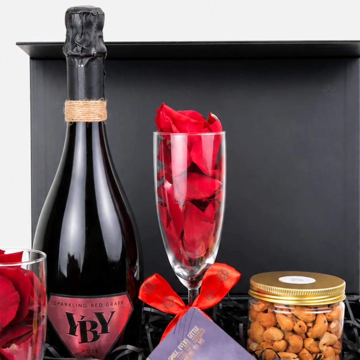 Premium nuts and sparkling beverage gift set with decorative rose petals and stylish presentation