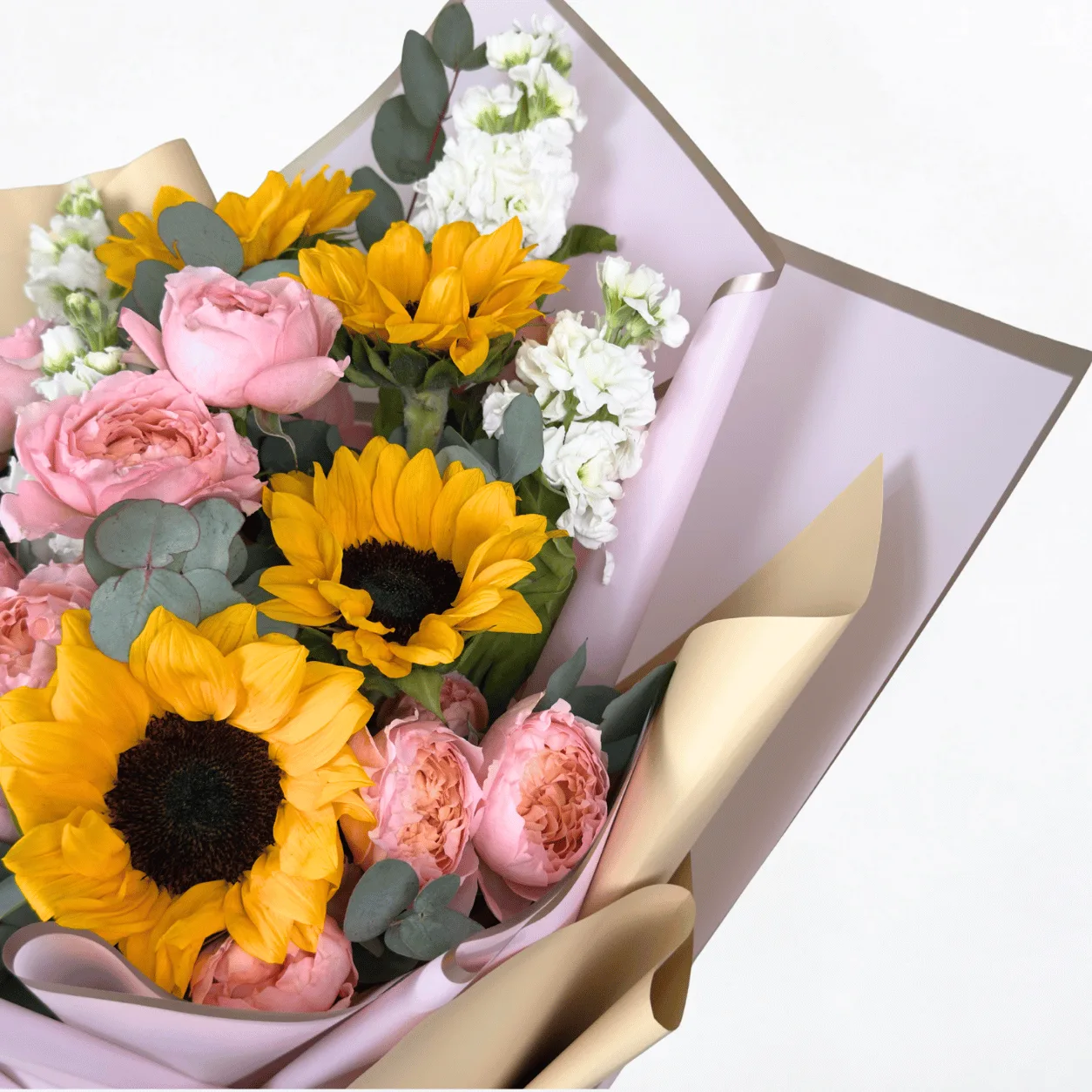 Bright sunflower and Juliet rose bouquet with fresh seasonal greenery in elegant wrapping.