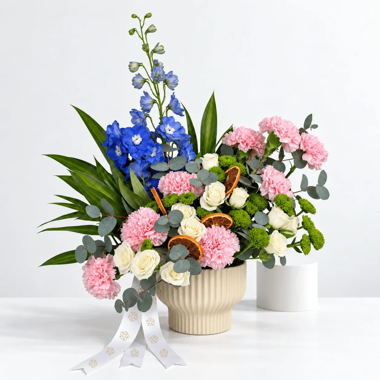 Whispers of Spring pink and blue floral arrangement in a cream ceramic pot for birthday gifting.