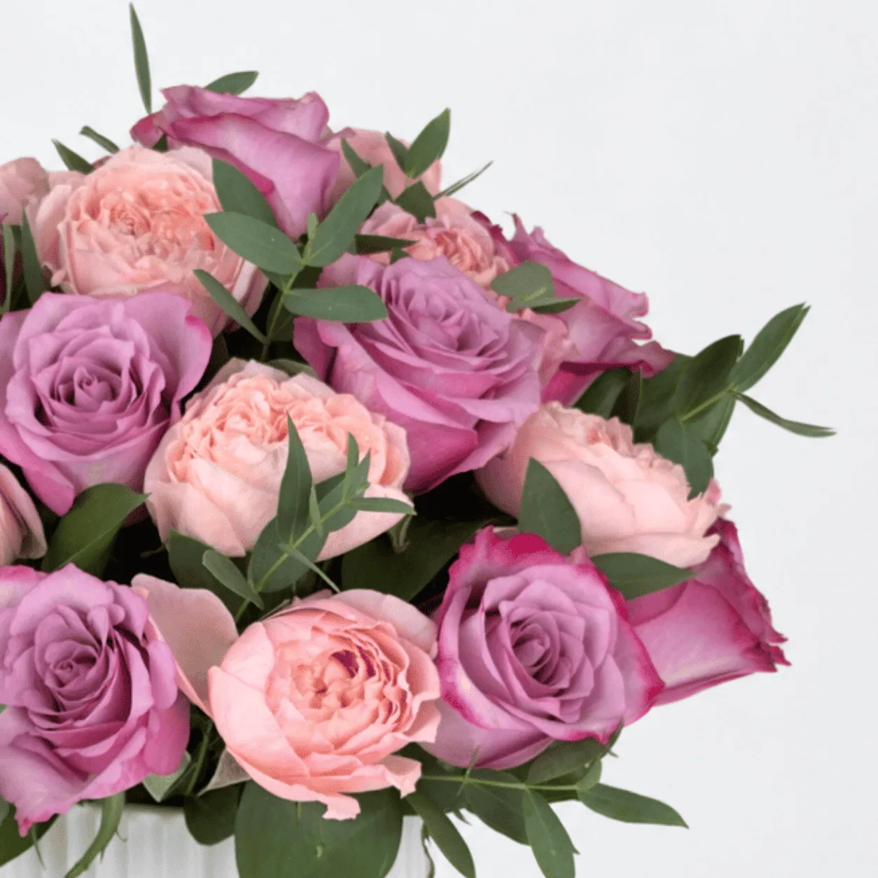 Purple and pink rose arrangement in a ribbed ceramic pot for Mother’s Day gifts.