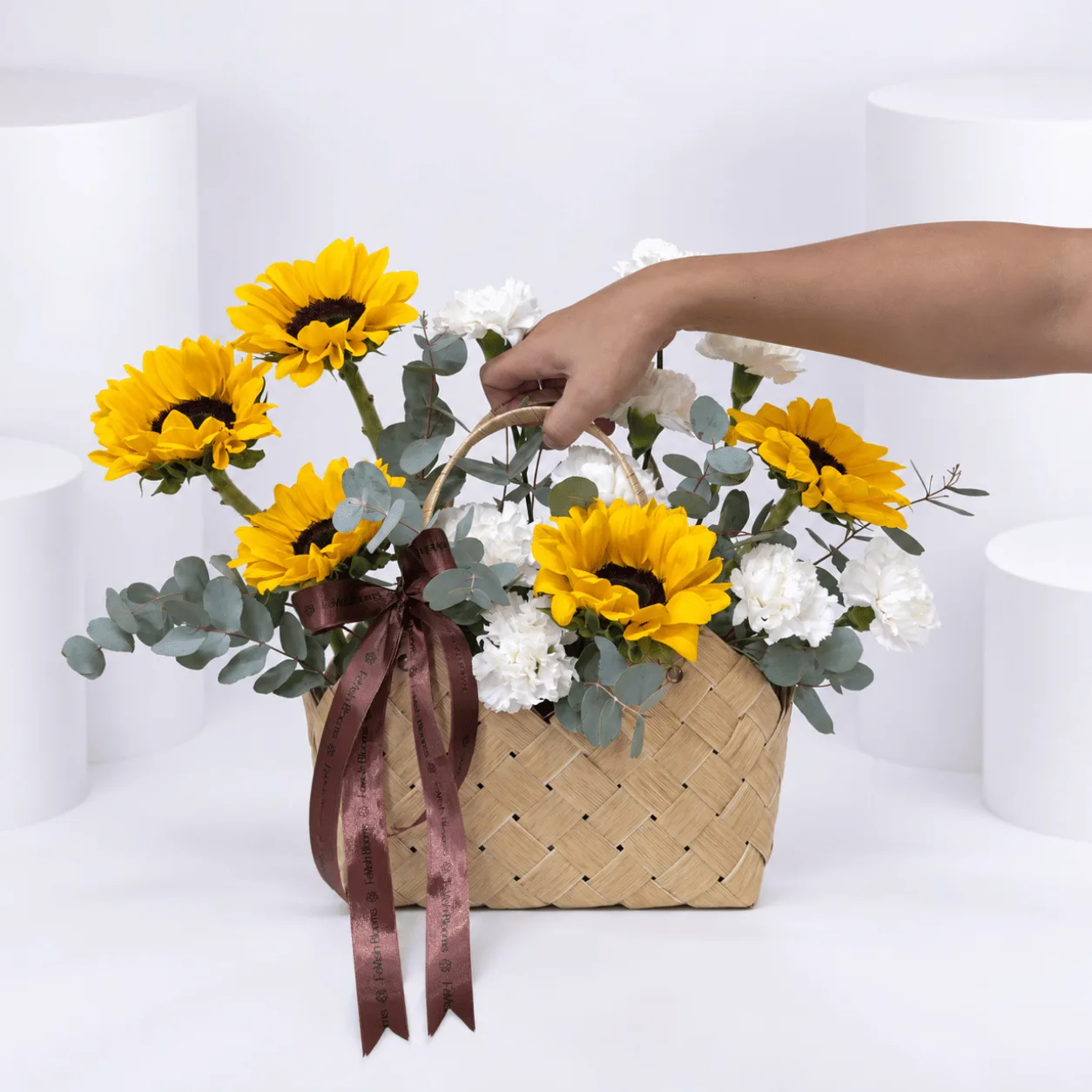 Elegant sunflower flower basket with vibrant golden blooms, delicate white carnations and a natural wicker handle.