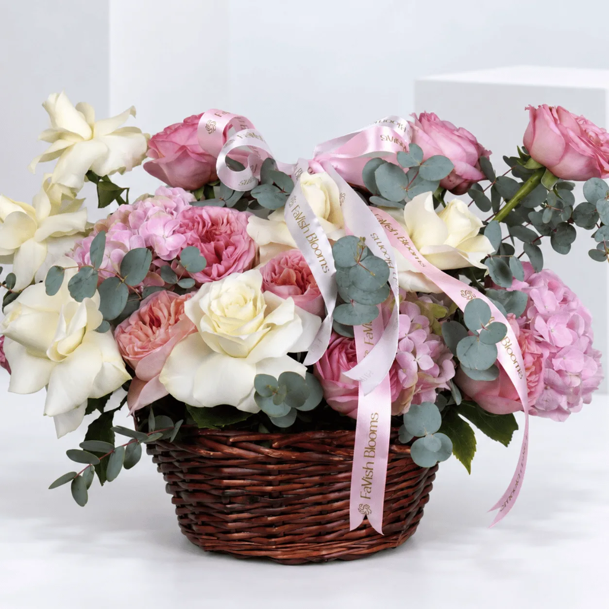 Romantic rose and hydrangea arrangement in a classic woven wicker basket, available for fresh flower delivery in Dubai and Sharjah.