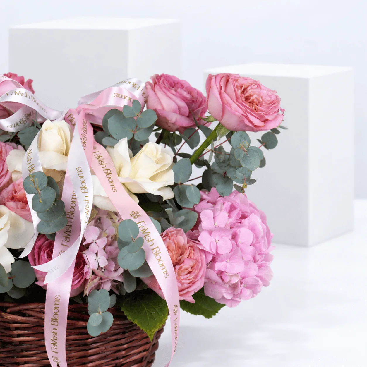 Close-up view of The Secret Garden Rose Basket showcasing delicate pink rose petals, ivory-white blooms, lush hydrangeas and eucalyptus foliage.