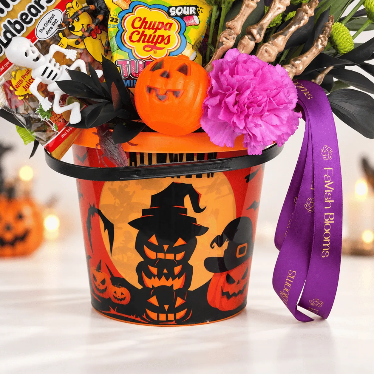 Side view of Halloween Candy & Fresh Flower Gift Bucket showcasing beautiful blooms, delicious candies, and festive Halloween decorations.