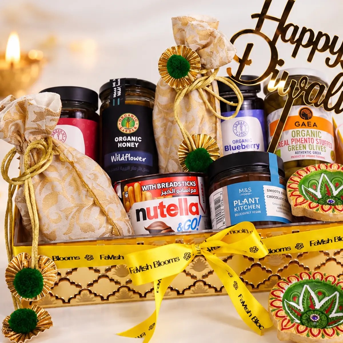 Luxury Diwali gourmet gift hamper with sweets, organic treats, decorative diyas, and golden packaging by FaVish Blooms.