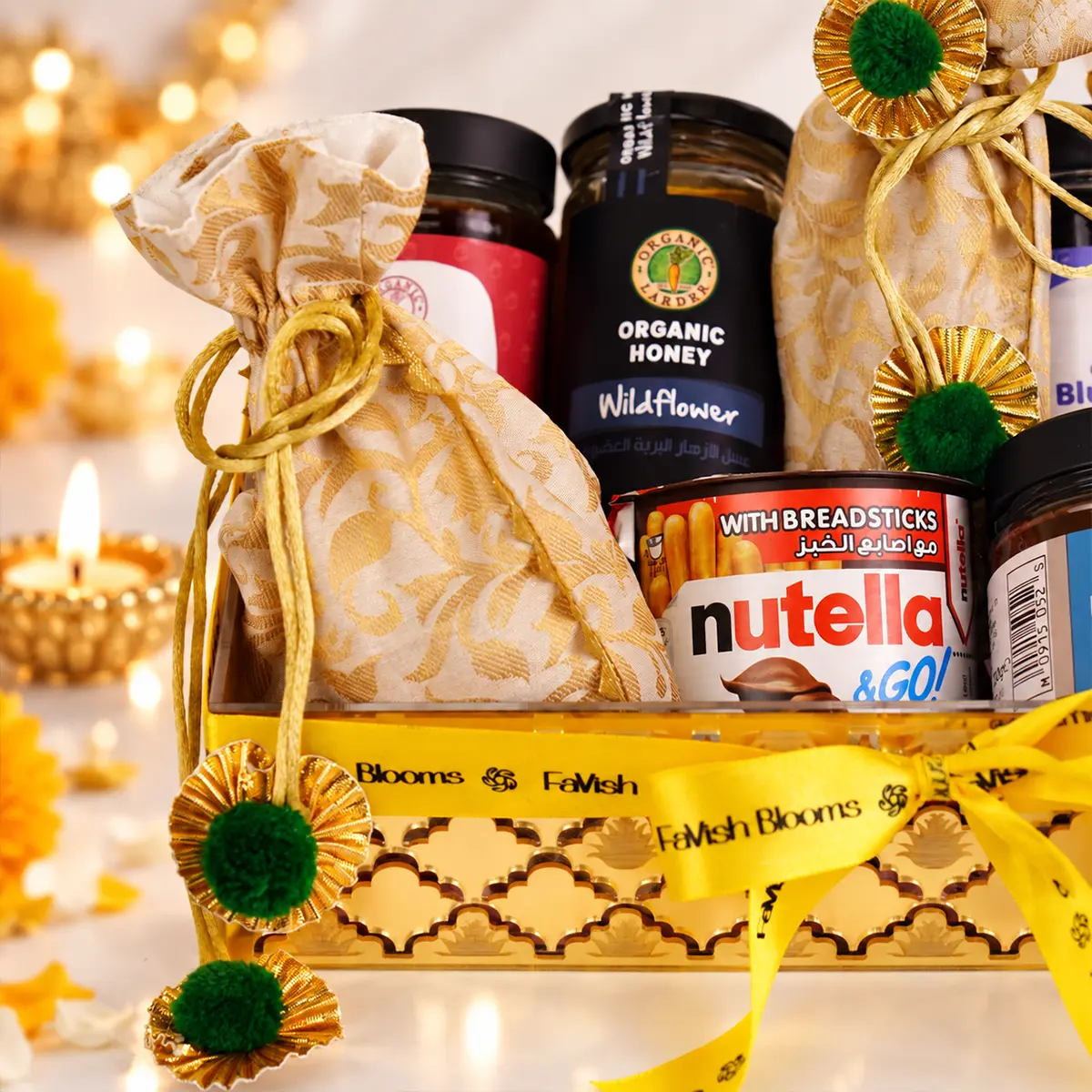 Close-up of Diwali gift hamper featuring organic honey, Nutella, festive potli, and golden packaging.