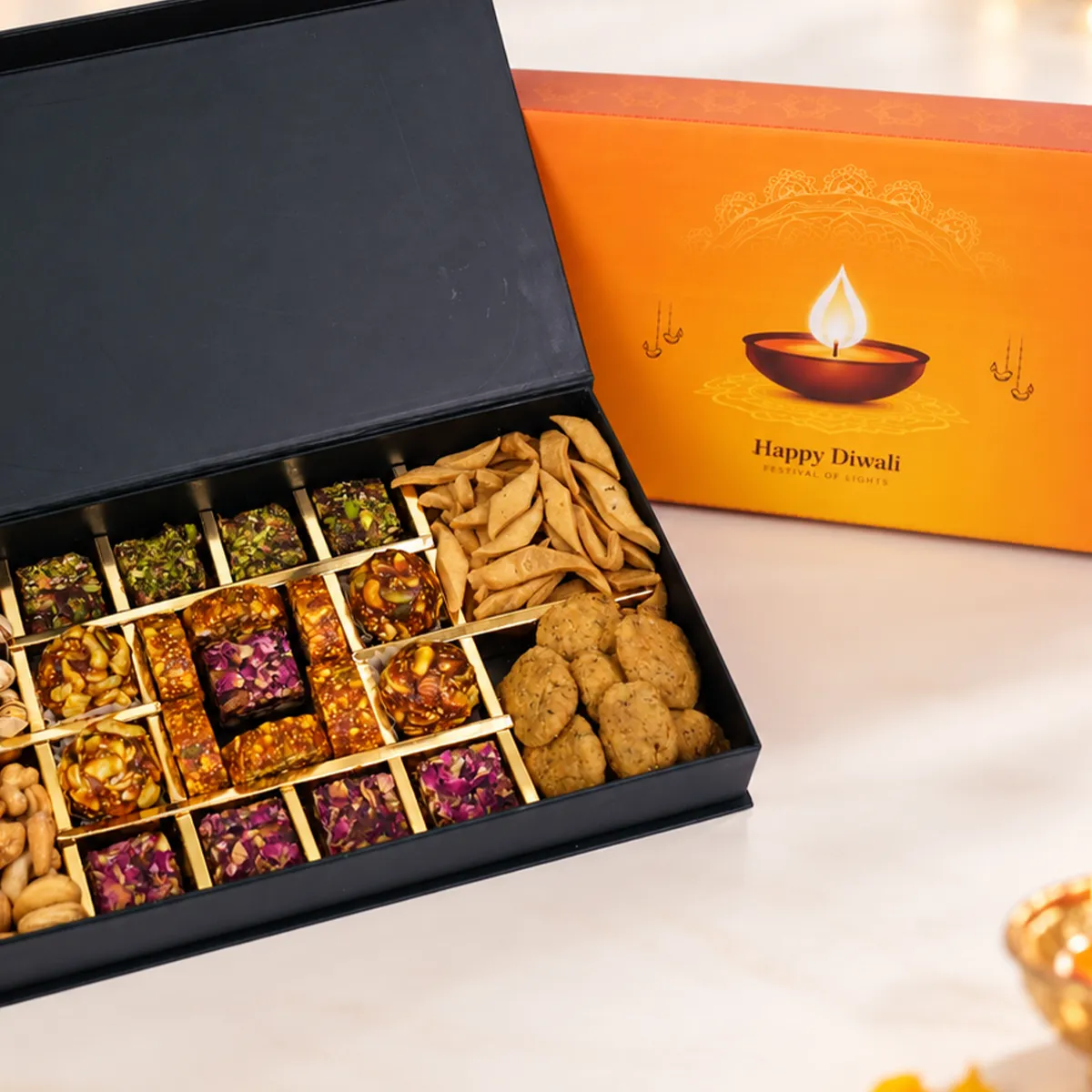 Premium Diwali gift hamper featuring assorted mithai, crispy snacks, and elegant black gift box.