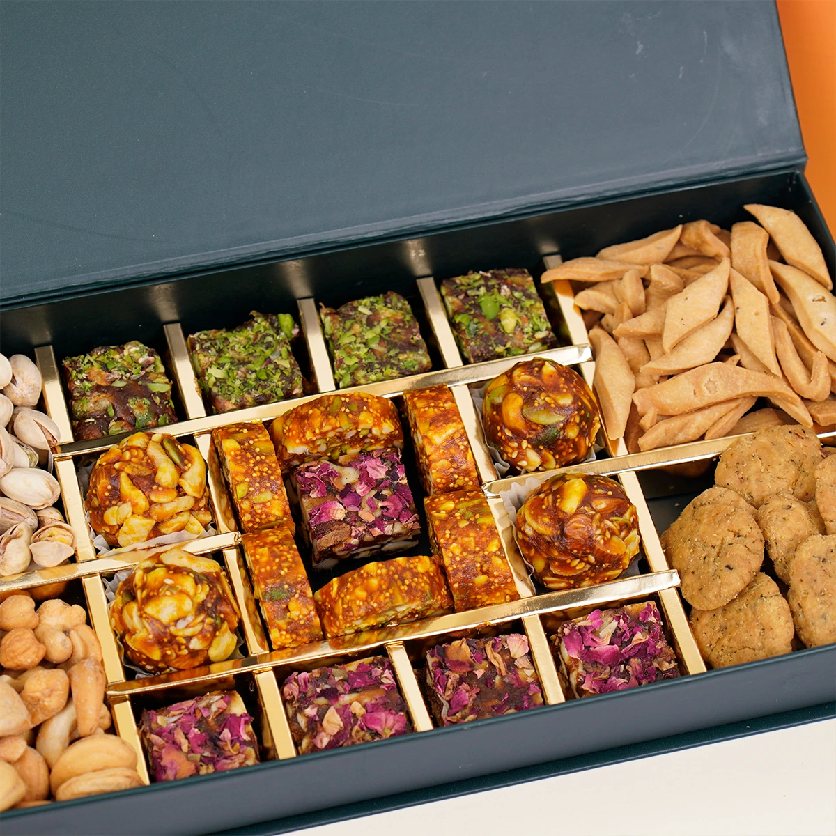 Close-up of premium Diwali mithai box with dry fruit sweets, rose petal treats, and savoury snacks.