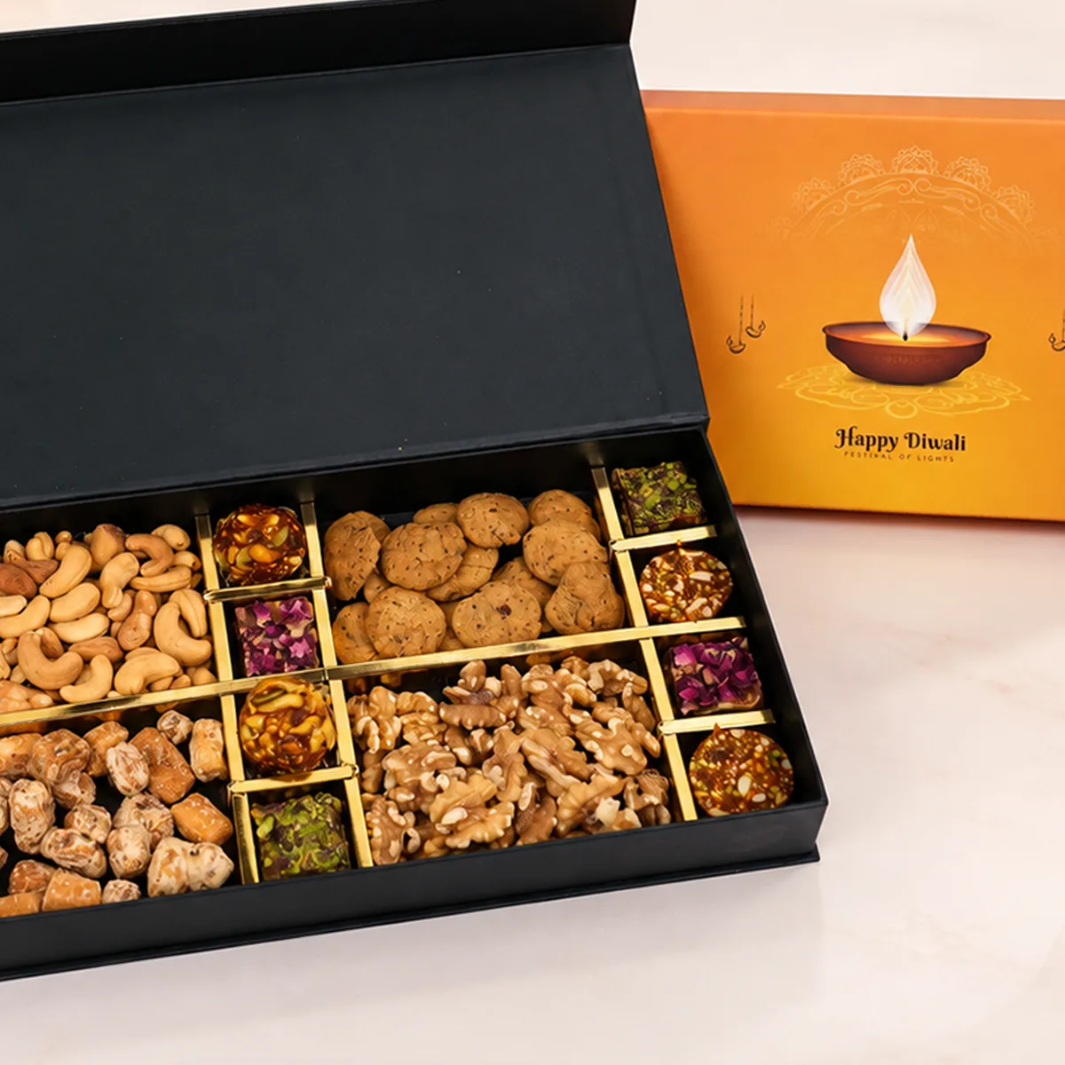 Close-up of Diwali dry fruits gift box with cashews, gurpara, walnuts, and festive mithai.