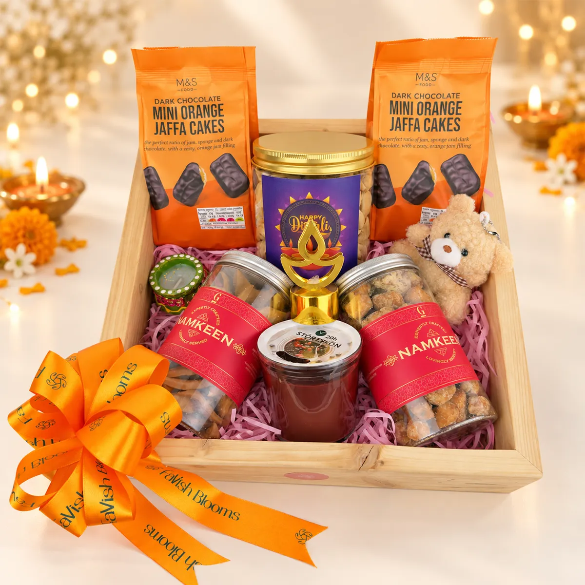 Premium Diwali gift hamper with Jaffa cakes, namkeen, dry fruits, teddy bear, and festive diyas.