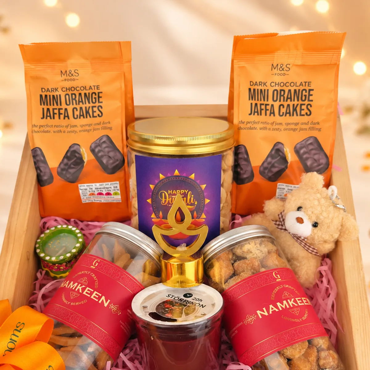 Diwali gourmet gift basket with M&S Jaffa cakes, premium snacks, teddy bear, and traditional diya.