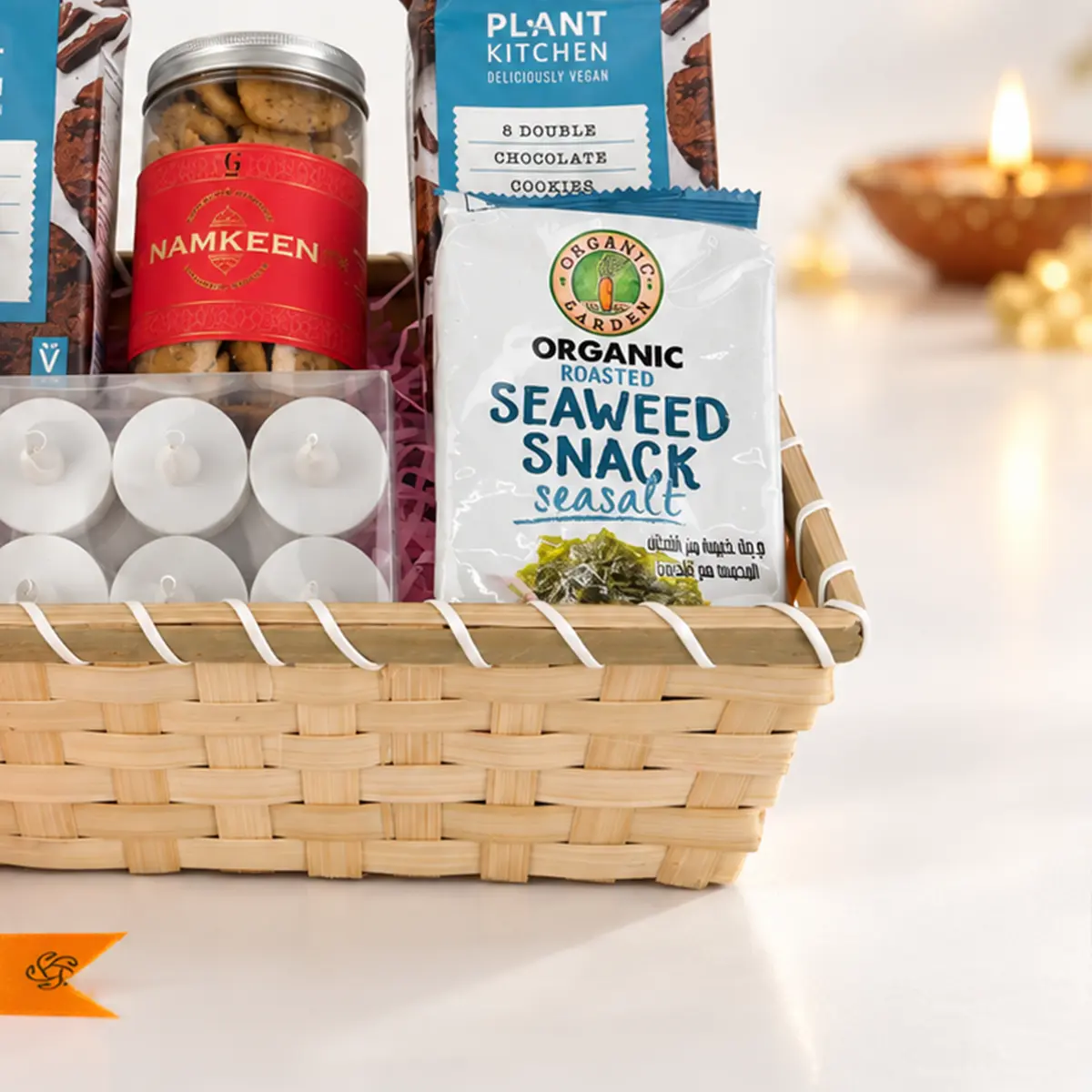 Detailed view of organic roasted seaweed snack, chocolate cookies, namkeen jar, and tealight candles inside a premium Diwali gift basket.