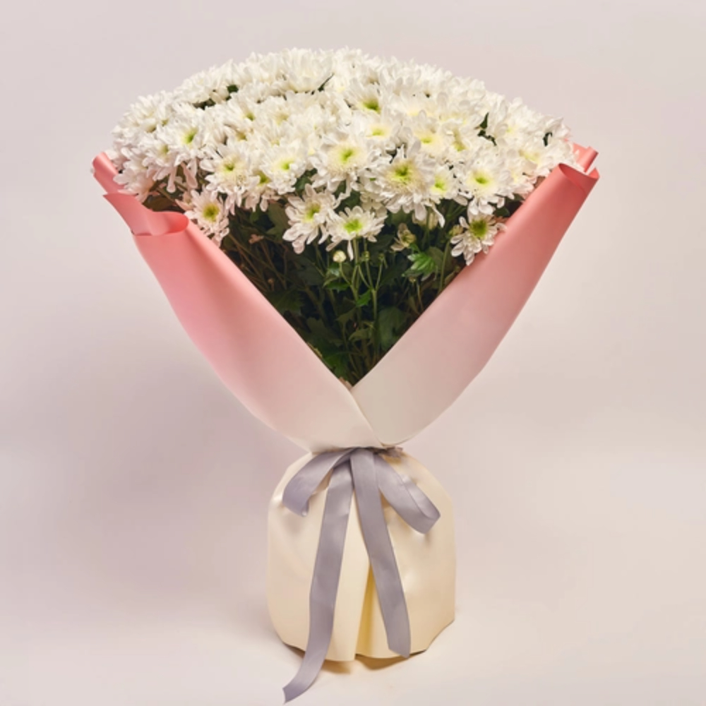 White daisy bouquet wrapped in soft pink paper with a satin ribbon