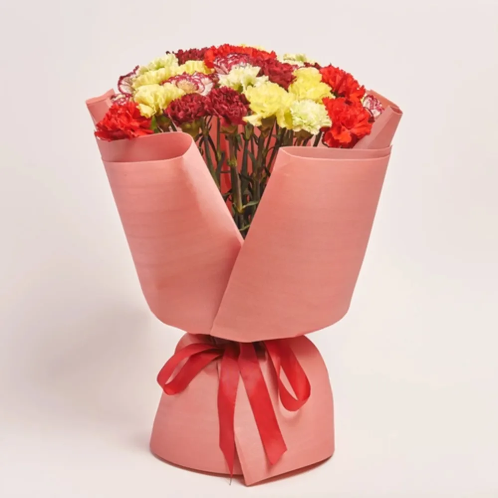 Mixed flower bouquet wrapped in soft pink paper with a matching ribbon