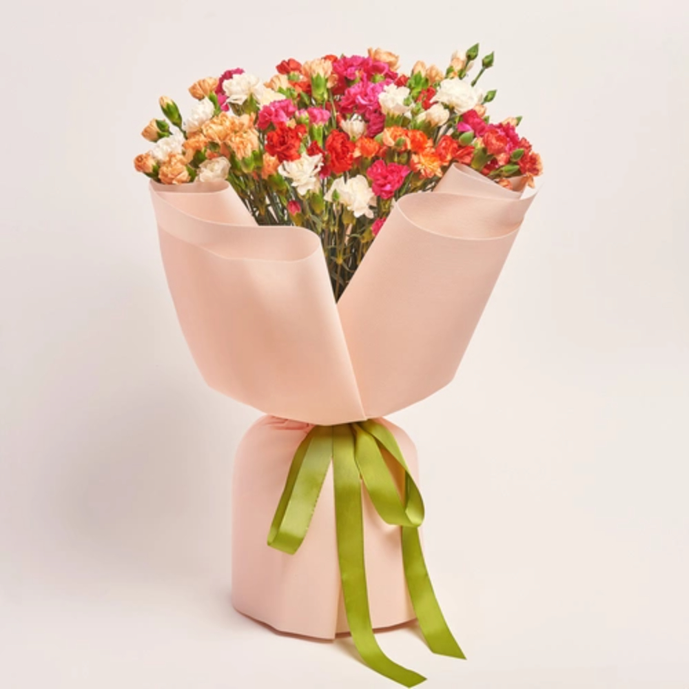 Delicate mixed flower bouquet wrapped in blush pink paper with green ribbon tails