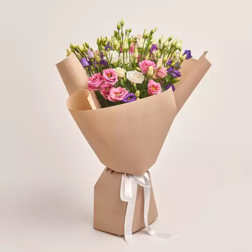 Mixed lisianthus bouquet in pink, white, and purple wrapped in kraft paper with a white ribbon