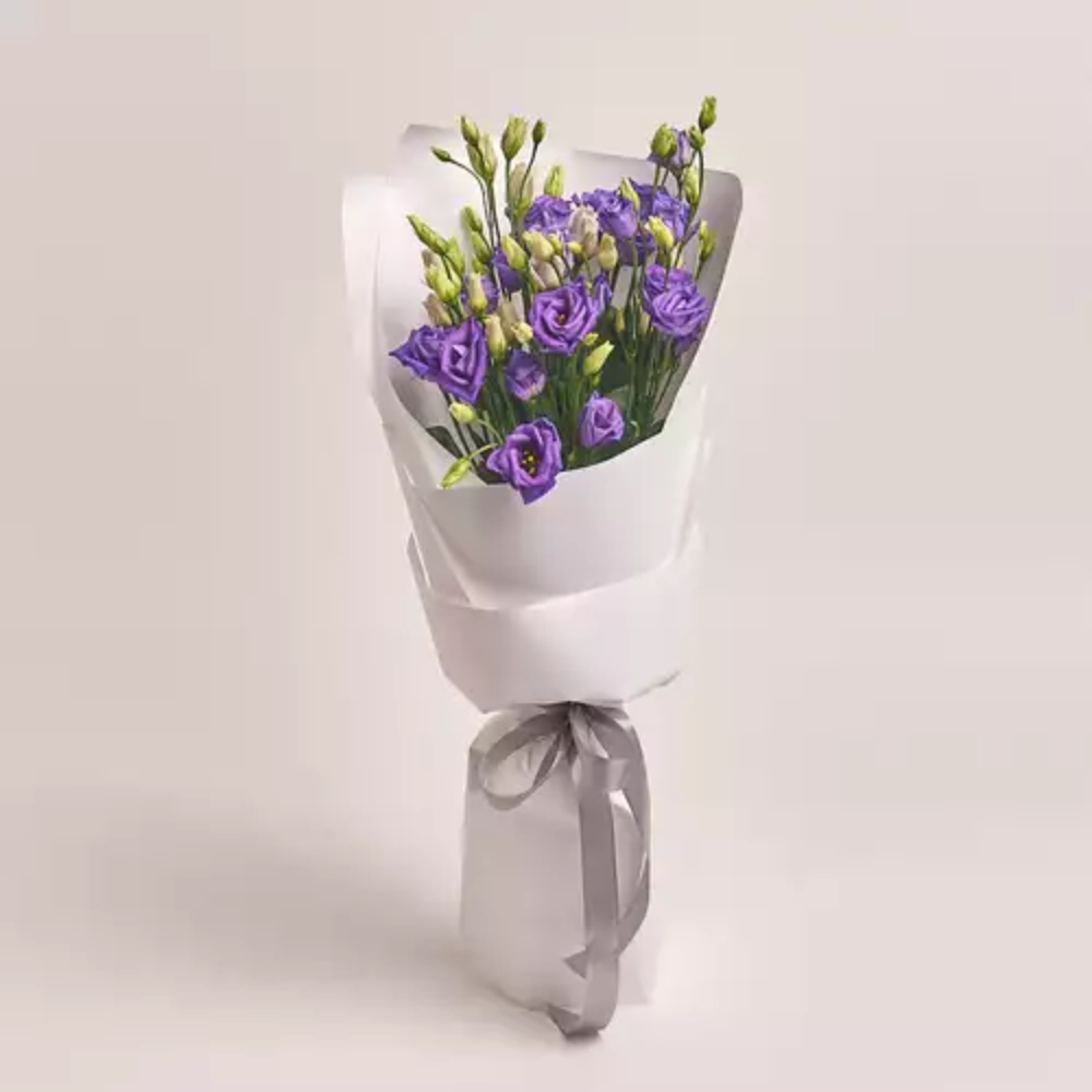 Purple lisianthus bouquet wrapped in white paper with a silver ribbon