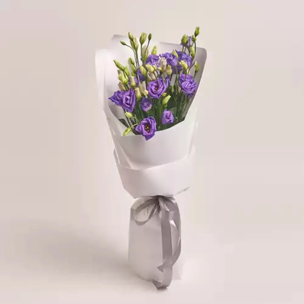 Purple lisianthus bouquet wrapped in white paper with a silver ribbon