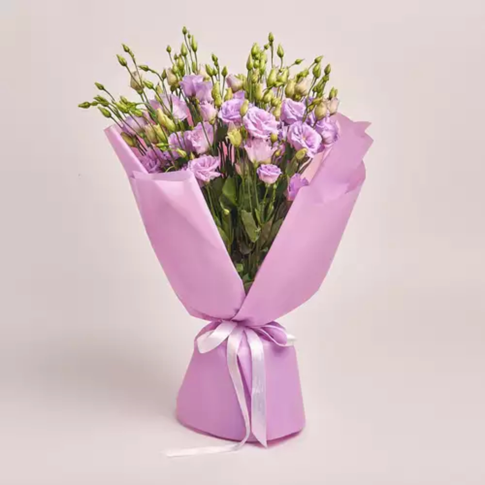 Purple lisianthus bouquet wrapped in soft pink paper with a white ribbon