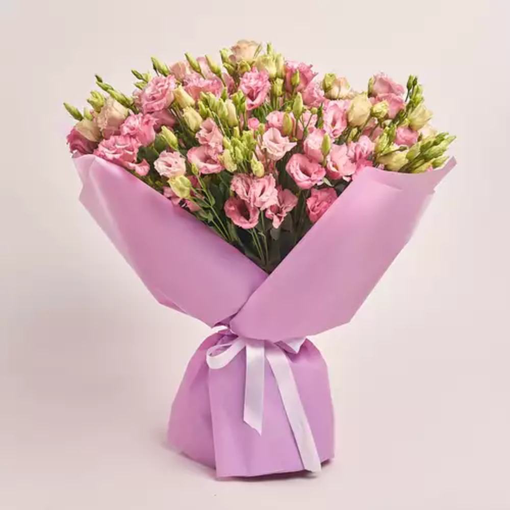 Pink lisianthus flower bouquet wrapped in soft pink paper with a white ribbon