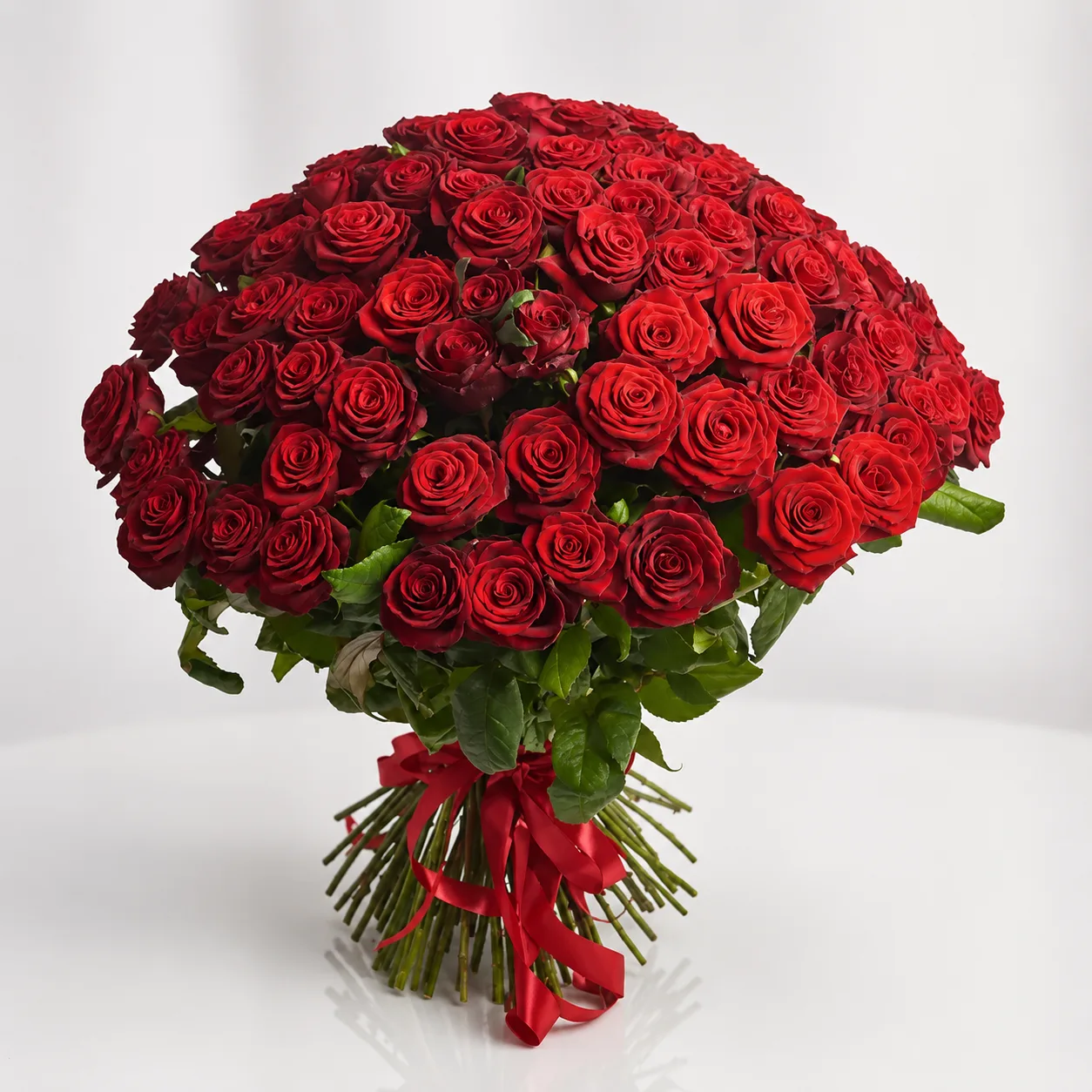 Large luxury bouquet of fresh red roses arranged in a full dome shape with green foliage and red ribbon, premium romantic gift by Favish Blooms Dubai
