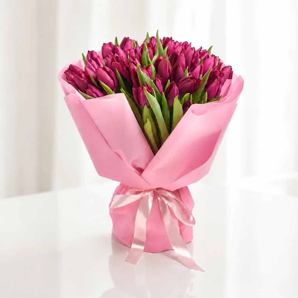 Luxury bouquet of fresh purple tulips wrapped in soft pink paper with a satin ribbon, elegant floral gift by Favish Blooms Dubai