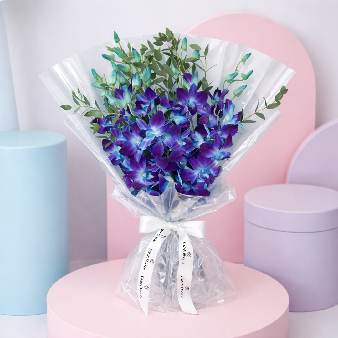 Blue and purple dendrobium orchid bouquet with eucalyptus wrapped in clear cellophane and tied with a white ribbon.