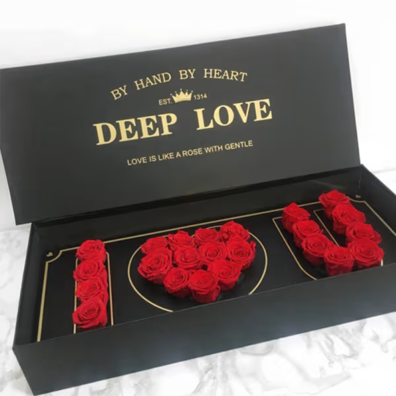 Red roses arranged in "I ♥ U" inside an open black "Deep Love" gift box with gold lettering.