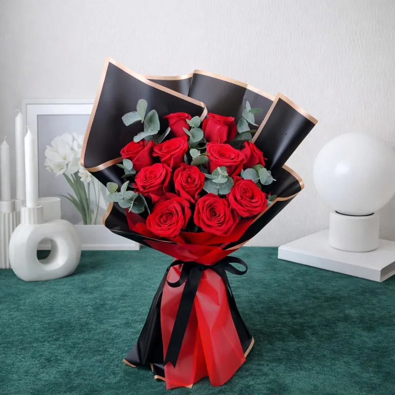 Red roses bouquet wrapped in black and red luxury paper with ribbon